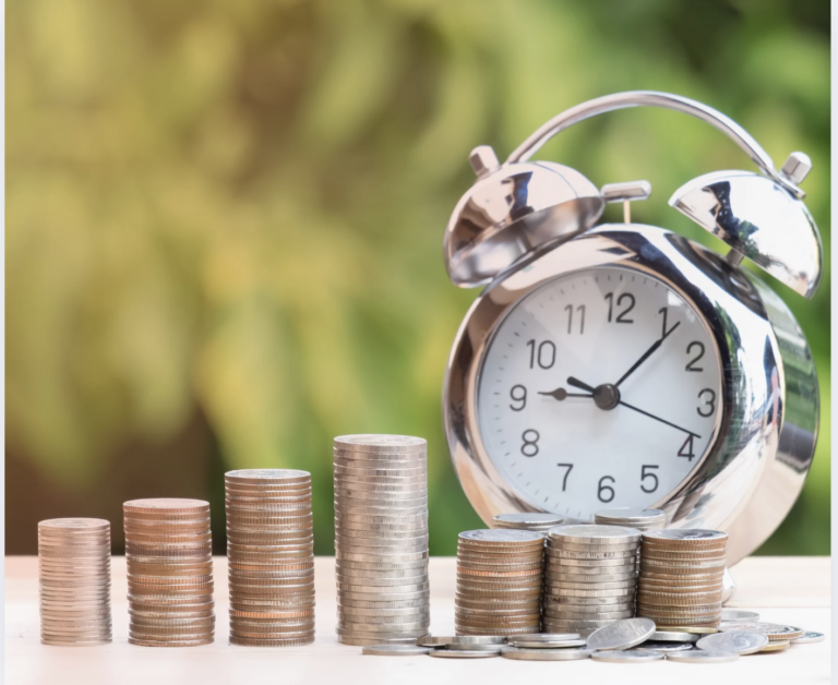 Stacked coins and a clock on a wooden desk